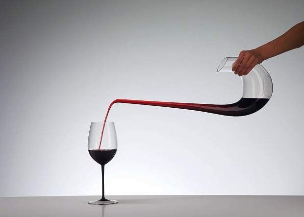 Roter Wein wird aus einer Karaffe in ein Weinglas gegossen
